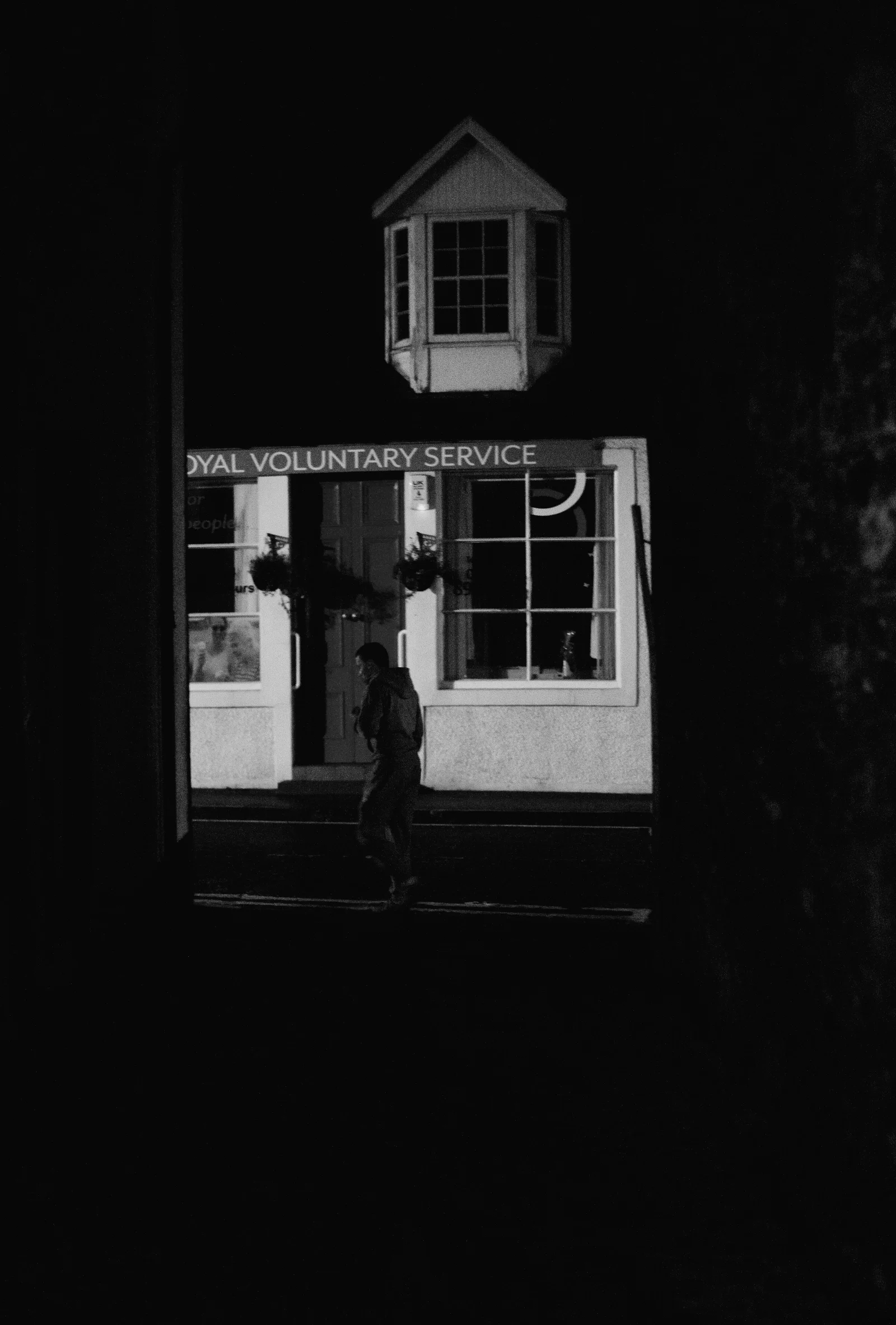 A lit doorway in a dark building suggests someone has just passed through.