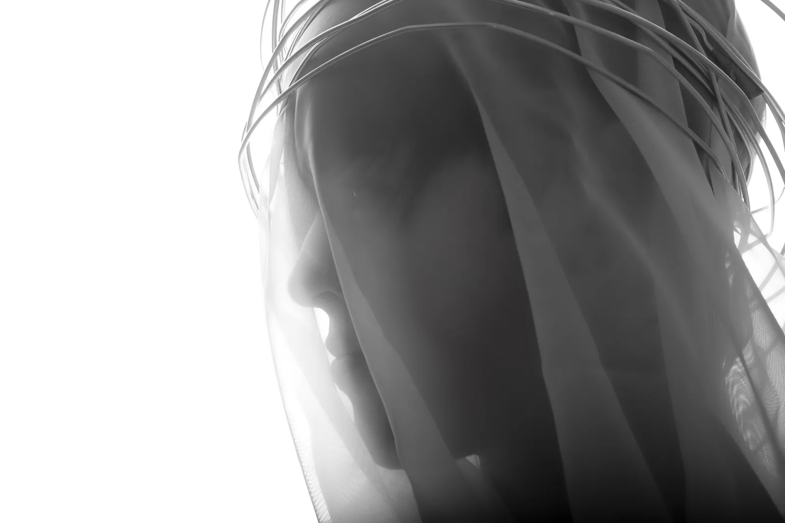 A layered high-key portrait dissolves into veils of white.