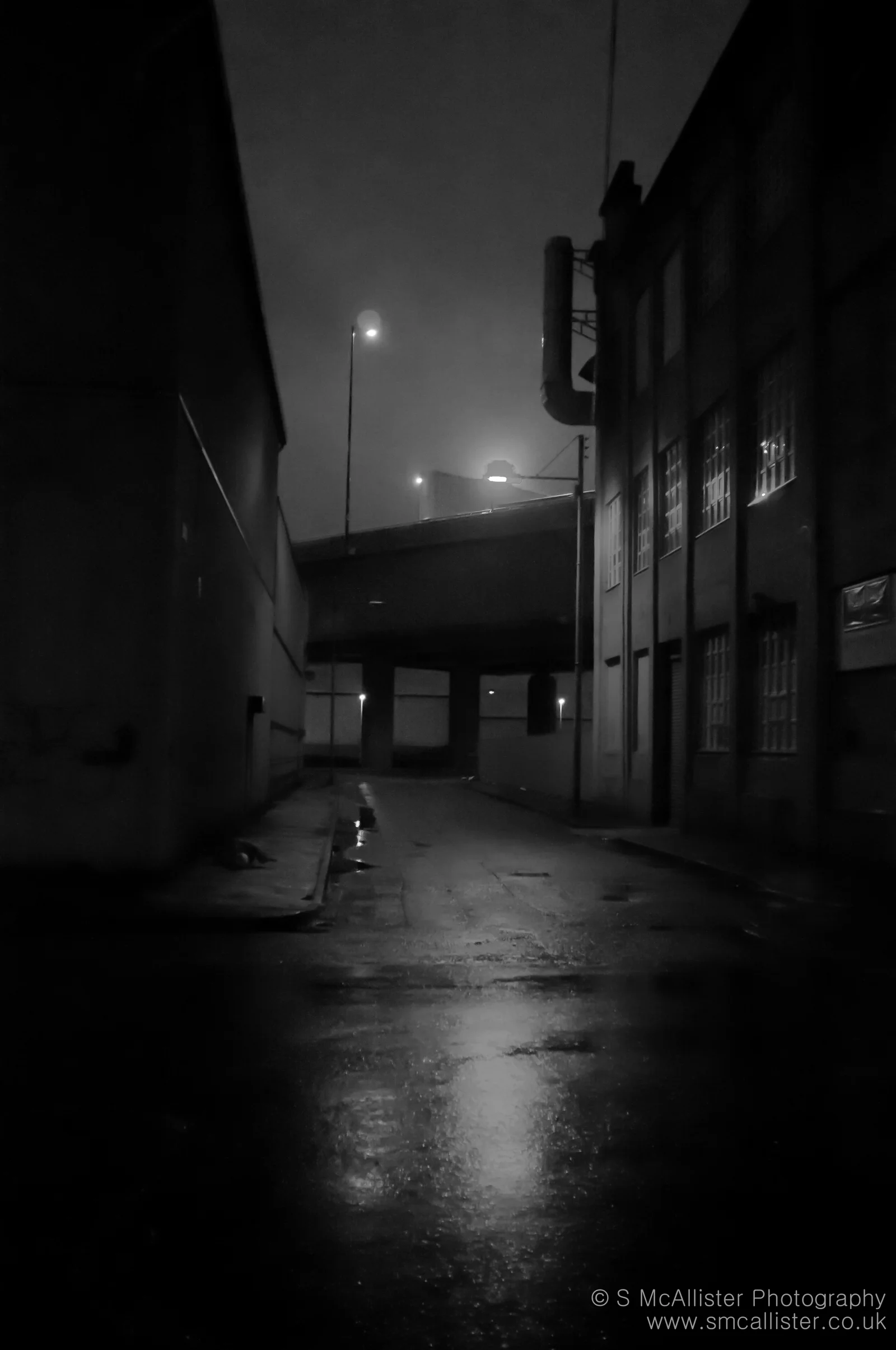 A deserted street disappears into mist and shadow.