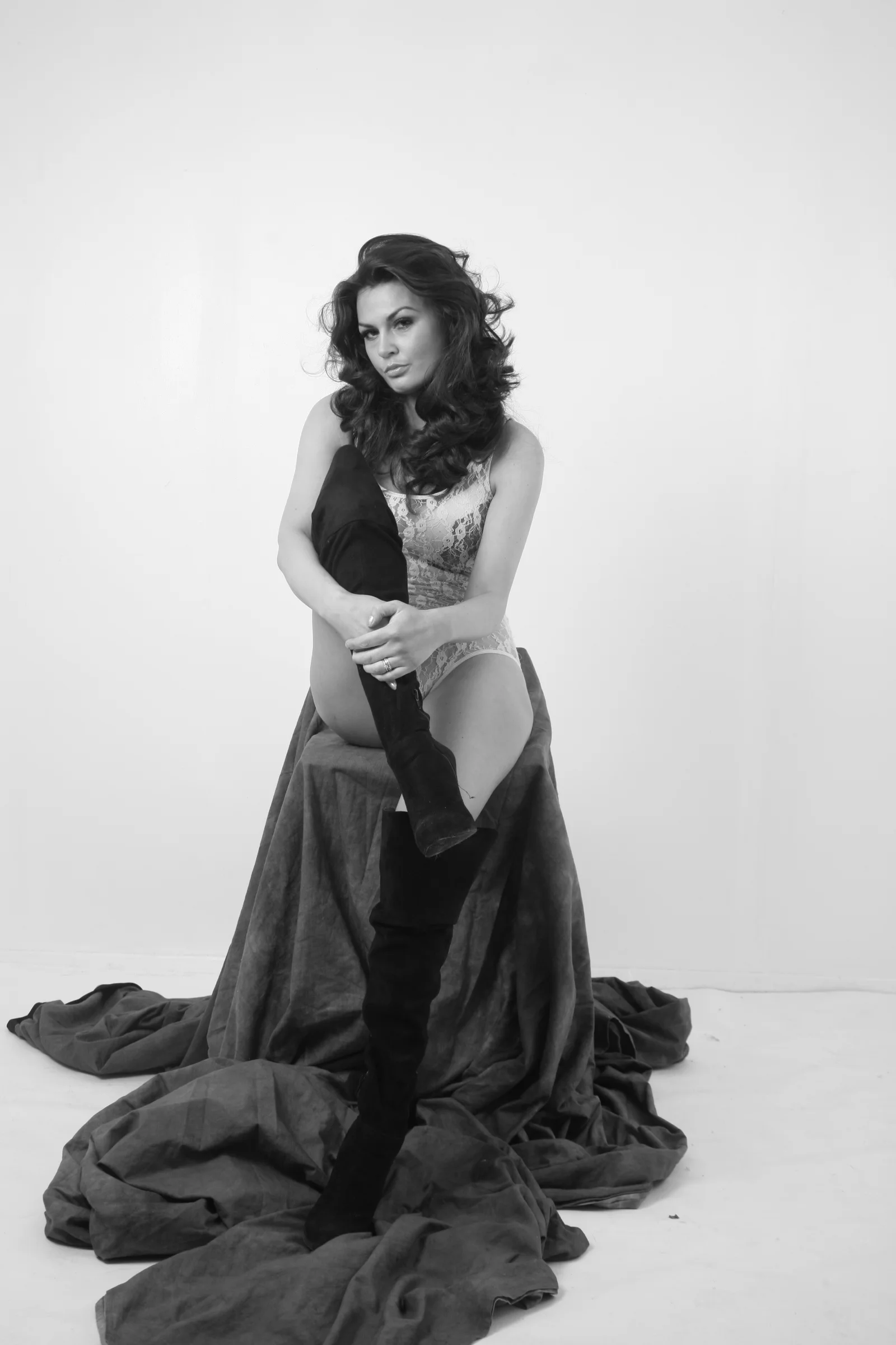 A woman stands in a long dark dress against a white studio background.